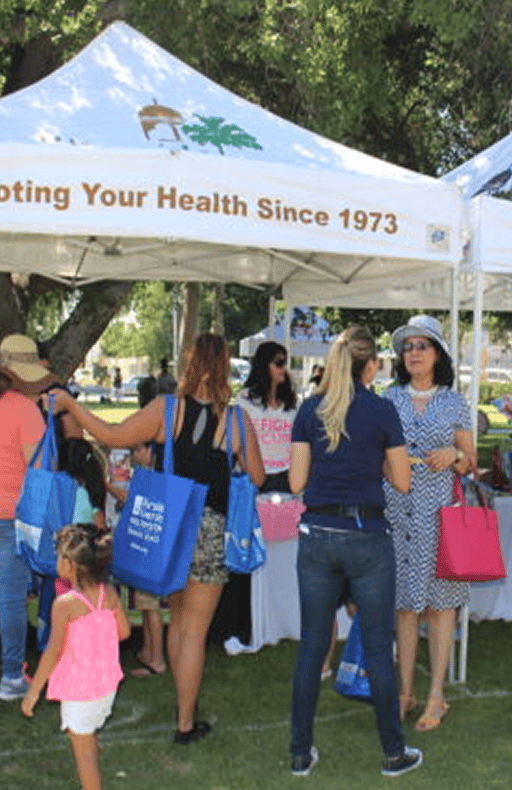 Families visiting a Riverside Community Health Foundation tent at an outdoor community health event
