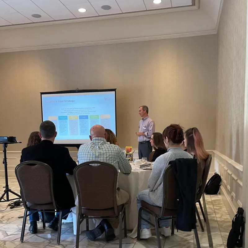 ClearPoint Strategy team at an offsite in Baltimore, seated around tables for a presentation