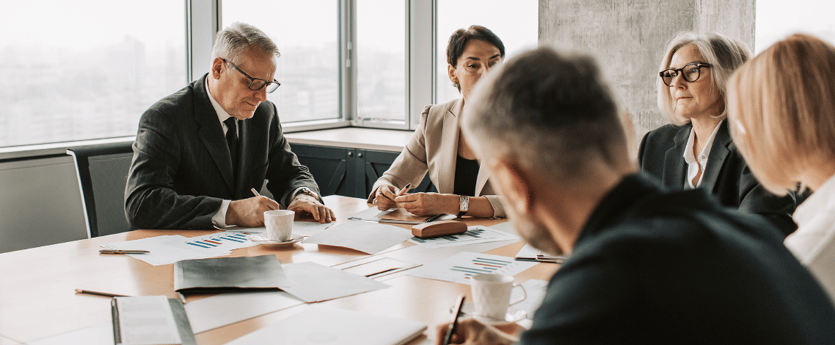 Executives reviewing printed charts and reports around a conference table